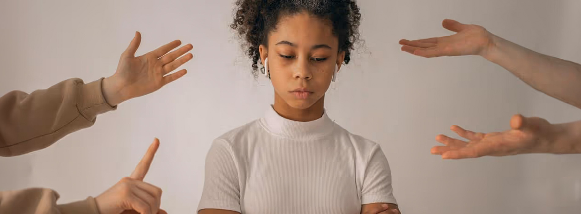 The image shows a person with their eyes closed, surrounded by multiple hands reaching towards them from different directions, against a plain background.