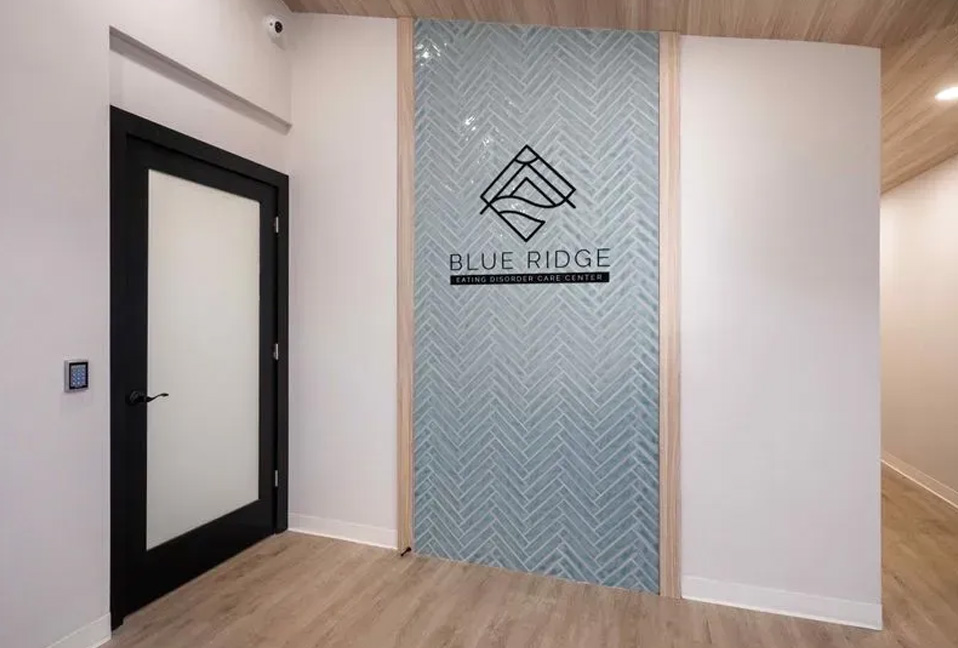 The image shows a modern interior space with a glass wall partitioning two areas, featuring a sign that reads BLUETIDE with a logo underneath.