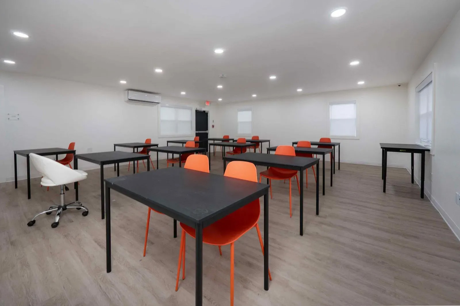 A classroom setting with multiple tables and chairs, ready for use.