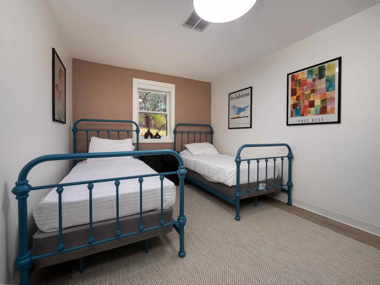 Two twin beds with blue frames in a room with white walls.