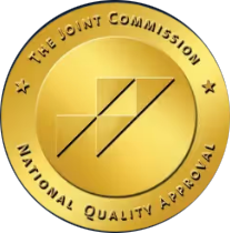 The image features a circular logo with text around its perimeter that reads 'THE JOINT COMMISSION' at the top, followed by 'NATIONAL QUALITY APPROVED' below it, and an emblem of a checkmark in a shield shape. The central part of the logo displays a golden star with the letters 'JCAH' inside it.